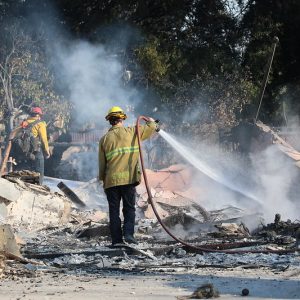 A crew hoses down the smoldering remains of a building in Altadena.