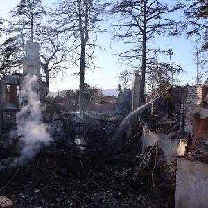 A firefighter hoses down a property destroyed in the Eaton Fire.