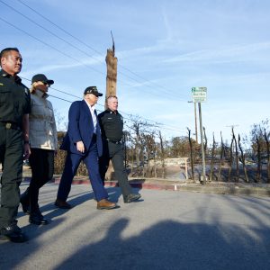 President Donald Trump, third from left, walks with first lady Melania Trump and local officials through a fire-ravaged neighborhood in Pacific Palisades.