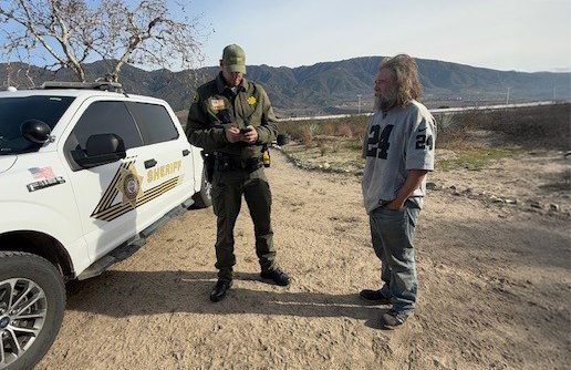 A San Bernardino County sheriff's deputy speaks with a man during a homeless outreach operation Jan. 31 in the San Bernardino area.