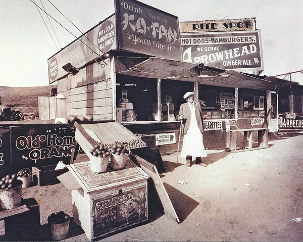 Lionel Sternberger is said to have invented the cheeseburger in the mid-1920s at this roadside snack stand on Colorado Boulevard in Pasadena. Pictured is Lionel's father, Herman Sternberger. The stand was later rebuilt as a restaurant named the Rite Spot. The photograph was displayed in at least one restaurant later operated by the family and appears to have been labeled to reflect the franchise name.