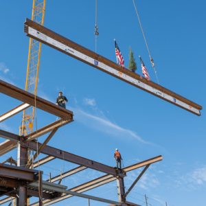 A ceremonial tree flanked by American flags heads toward the top of the Wellness Village construction project in Mead Valley.